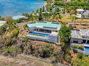 Ein modernes Haus mit Schwimmbad, umgeben von üppiger Vegetation und Blick aufs Meer.