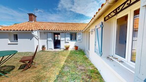 A house with a tiled roof, a door leading to a covered porch, a table, and potted plants. - Roche aux Mouettes - House 100m² and large garden (Saint-Jean-de-Monts)