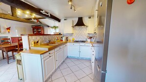 Een keuken met witte kastjes, een houten aanrecht, een fornuis en een koelkast.