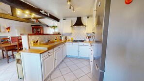 A kitchen with white cabinets, a wooden countertop, a stove, and a refrigerator. - Roche aux Mouettes - House 100m² and large garden (Saint-Jean-de-Monts)