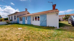 A two-story house with a tiled roof, a chimney, and a car parked in the driveway. - Roche aux Mouettes - House 100m² and large garden (Saint-Jean-de-Monts)