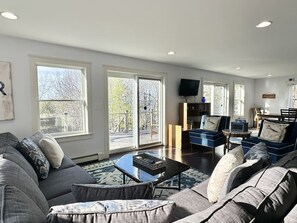 Ein geräumiges Wohnzimmer mit einer großen Couch, einem Couchtisch und einem an der Wand befestigten Fernseher.