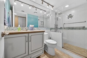 A modern bathroom with a shower, toilet, and vanity. - VAN LEE BEACH CONDO 204!!!! (Ormond Beach)