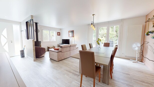 Un salon moderne avec un canapé, un téléviseur et une table à manger avec des chaises.