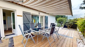 Eine überdachte Terrasse im Freien mit Tisch und Stühlen, einer Holzterrasse und Blick auf den umliegenden Garten.