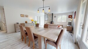 Un espace de salle à manger moderne avec une table en bois, des chaises en cuir et des luminaires suspendus.