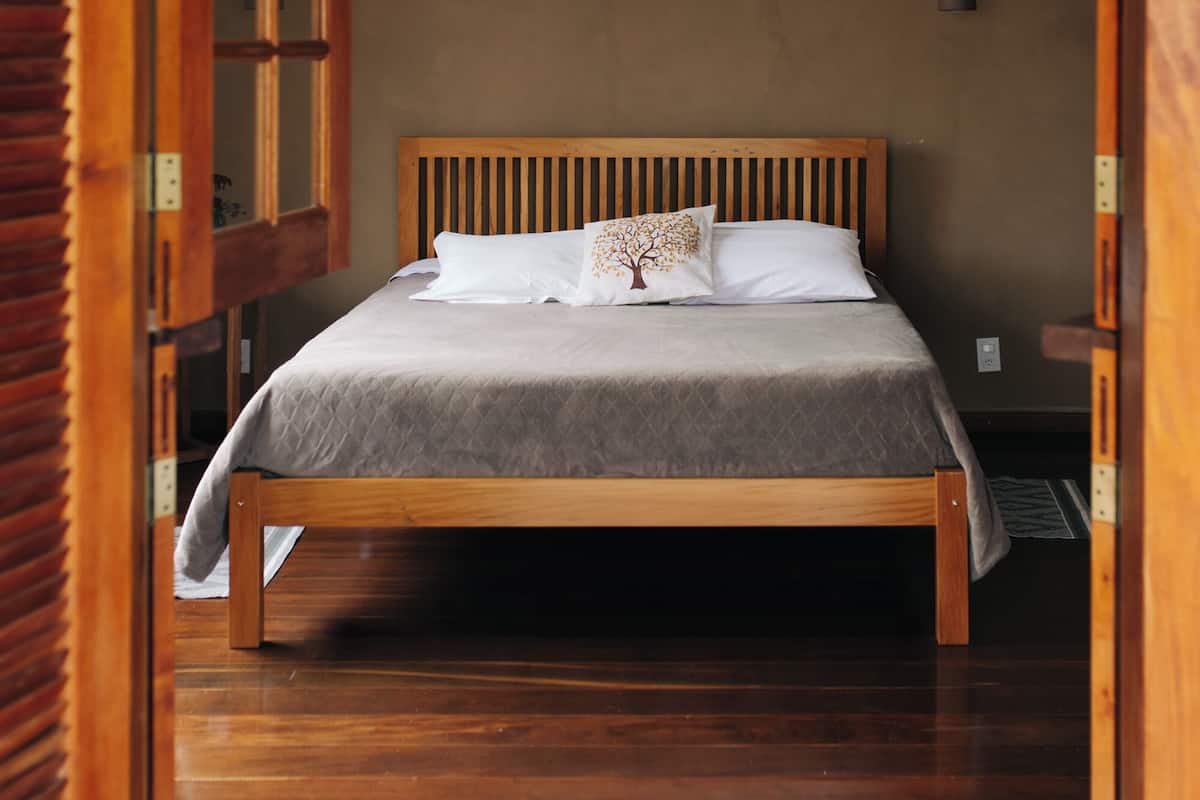 A wooden bed with a headboard, a ceiling fan, and a window with a view of the outside.