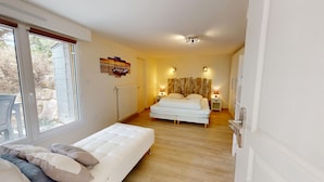 A bedroom with a bed, a bedside table, a lamp, a radiator, and a window. - Dune - Apartment 40m² with Terrace (La Barre-de-Monts)