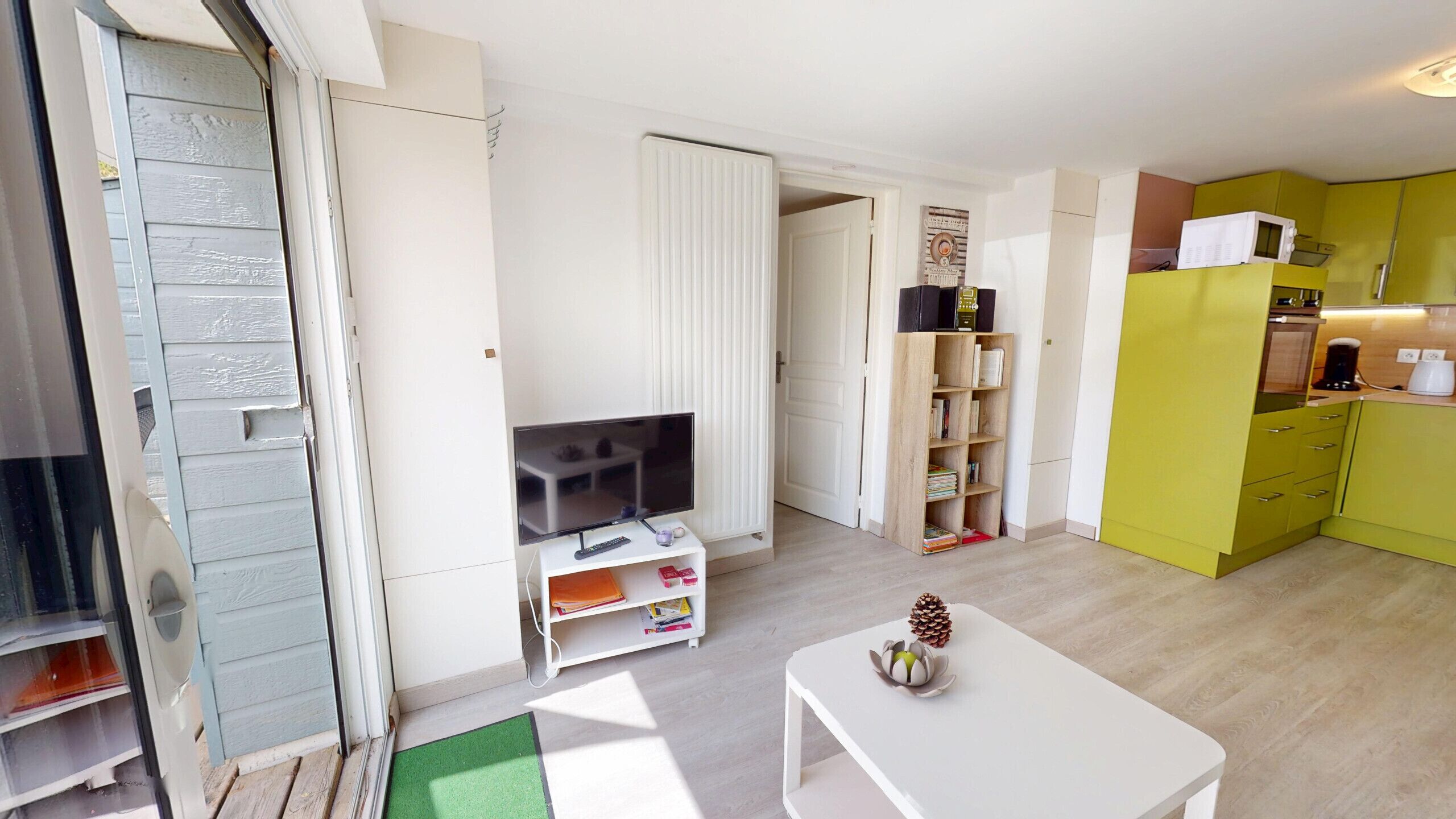 A compact living space with a television, bookshelf, and a small dining area.