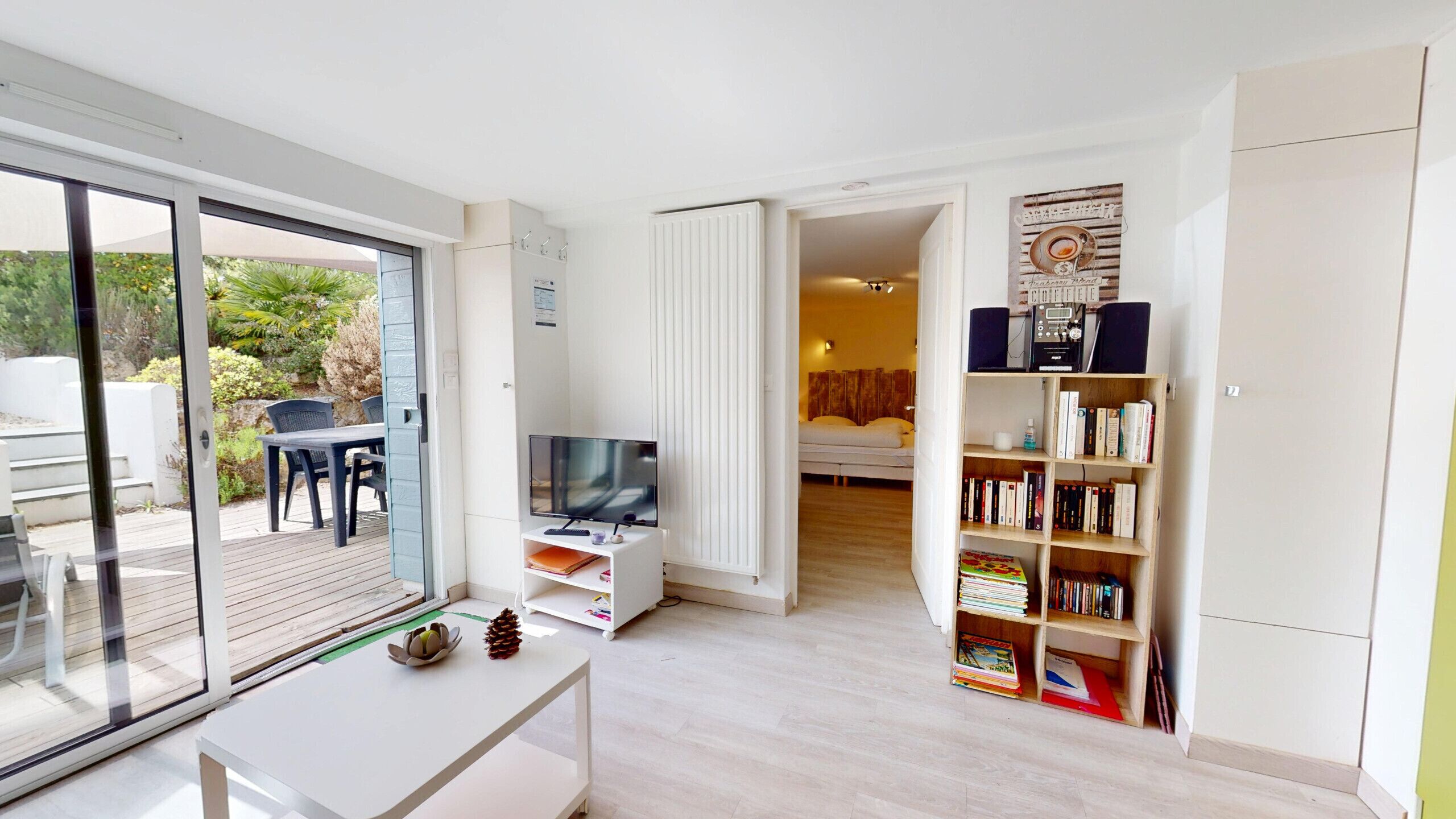 Ein modernes Wohnzimmer mit Fernseher, Bücherregal und Essbereich mit Sitzgelegenheiten im Freien.