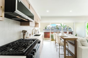 A modern kitchen with a gas stove, a microwave, and a large window overlooking a residential area. - Casa Marea - Boca Intracoastal Hideaway (Boca Raton)
