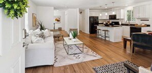A modern living room with a sofa, coffee table, and a kitchen area with a refrigerator, microwave, and bar stools. - The Arbordale: 9-Acre, Redwoods, Secluded (Sebastopol)
