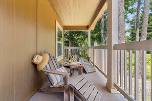 A wooden deck with two lounge chairs, a table with a bottle and sunflowers, and a straw hat leaning against the wall. - The Arbordale: 9-Acre, Redwoods, Secluded (Sebastopol)