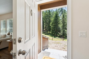A door leading to a forested outdoor area with a wooden deck and a white wall with a light switch. - The Arbordale: 9-Acre, Redwoods, Secluded (Sebastopol)