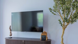 Seinälle asennettu litteänäyttöinen televisio, jonka yläpuolella on puinen konsolipöytä ja sen päällä ehdotuslaatikko.