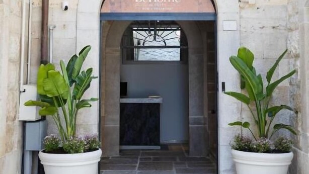 An entrance to a building with a sign reading 'BeHome.' There are two potted plants on either side of the entrance. - BeHome al Porto (Trani)