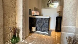 A stone-floored lobby with a reception desk, a lamp, and two vases. - BeHome al Porto (Trani)