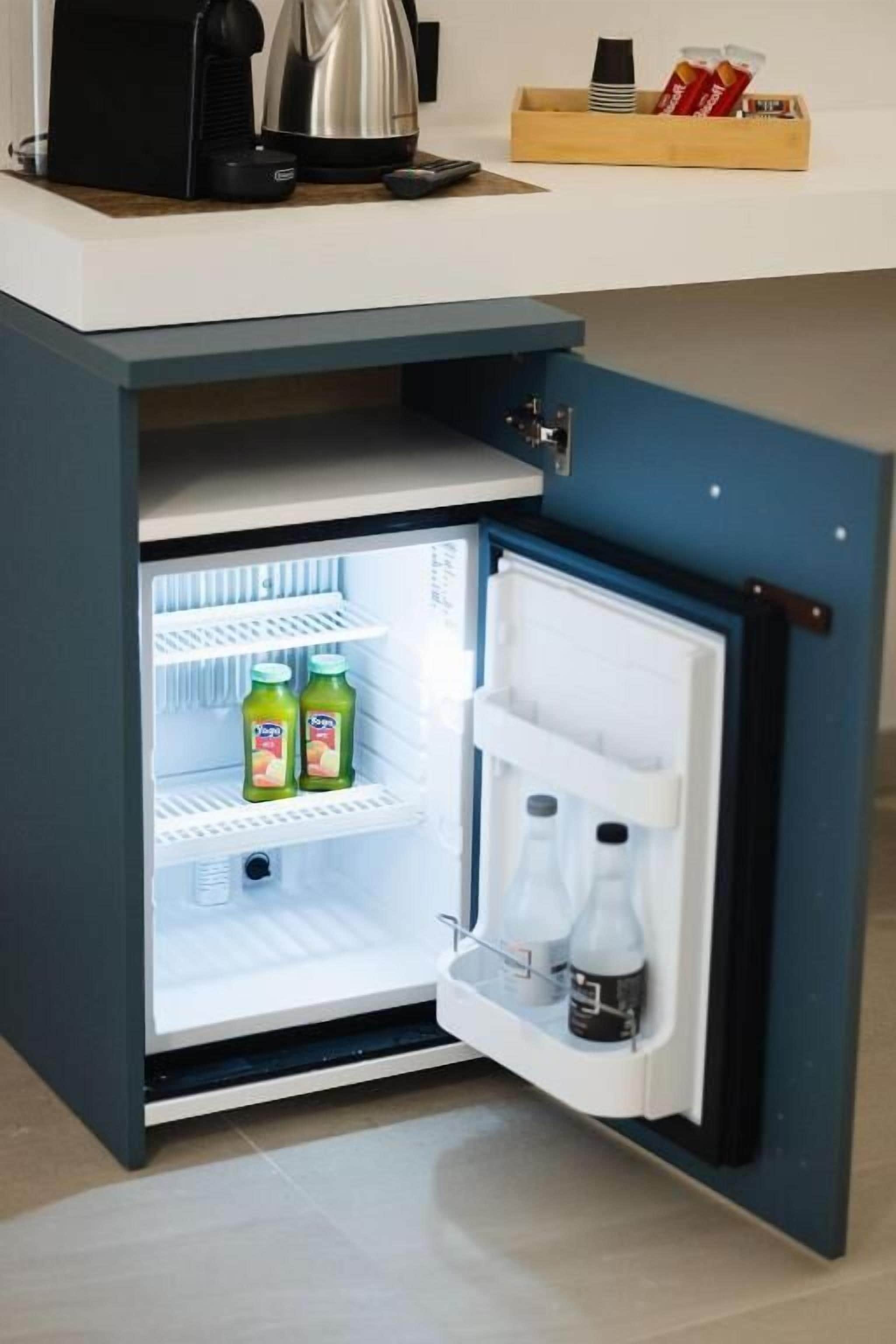 A compact refrigerator with a built-in coffee maker, a small shelf, and a drawer.