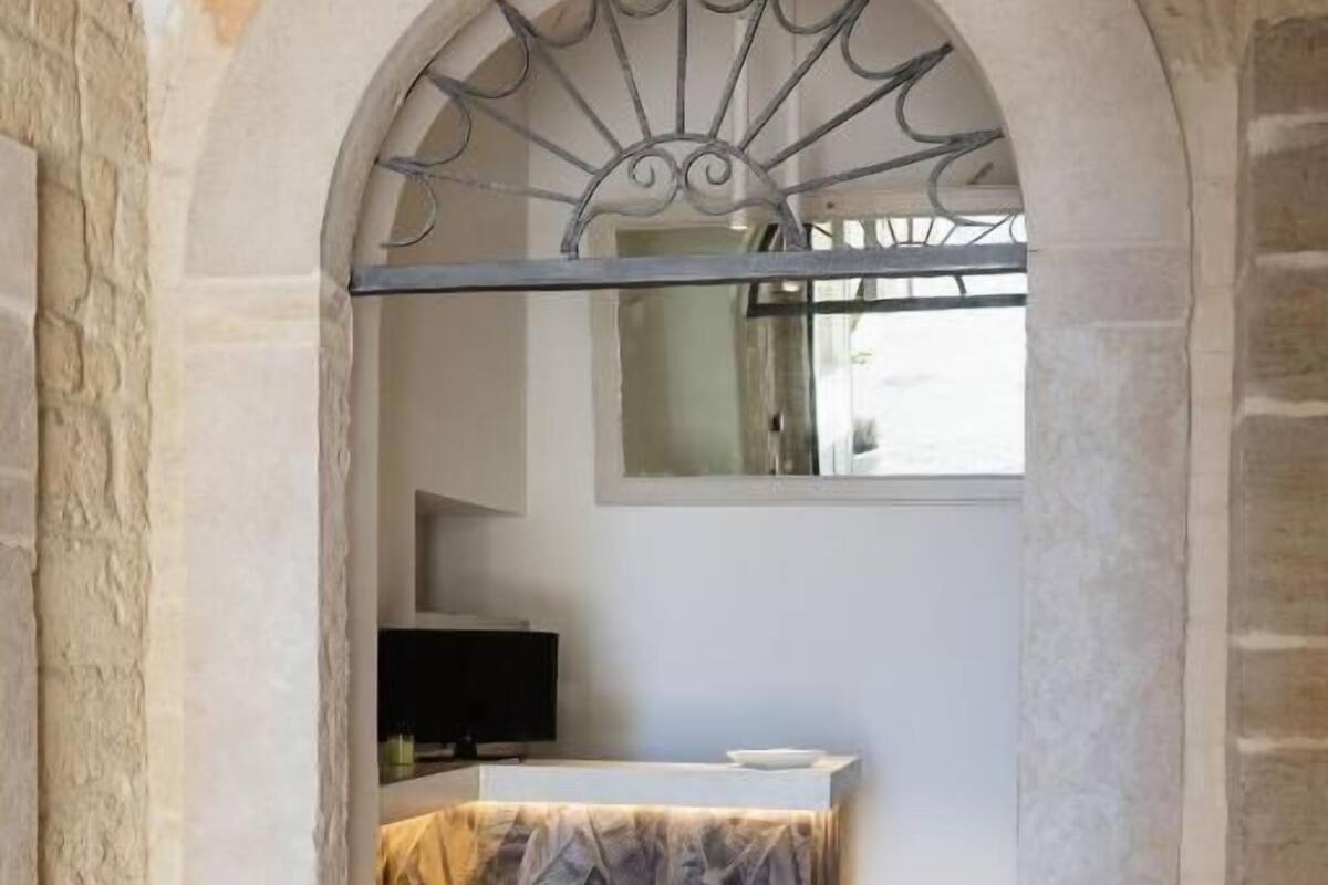 Un baño con paredes de piedra, suelo de baldosas, un lavamanos y un espejo sobre él.