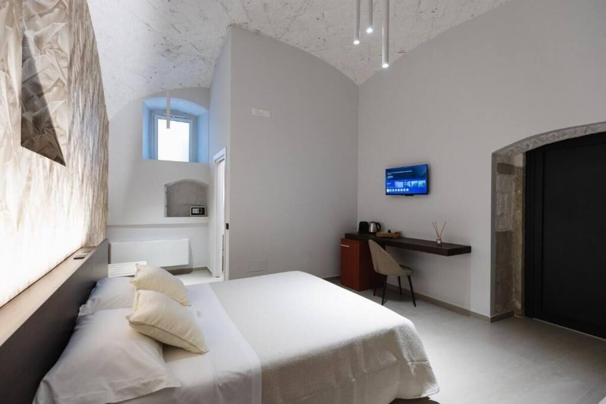 Un dormitorio moderno con una cama, un escritorio, un televisor y una chimenea.