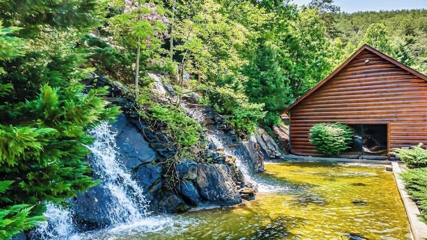 Eine Holzhütte mit Wasserfall und Teich.