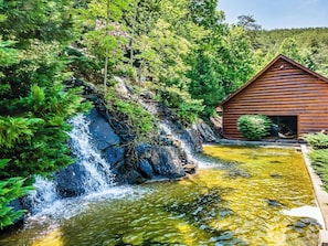 Eine Holzhütte mit Wasserfall und Teich.