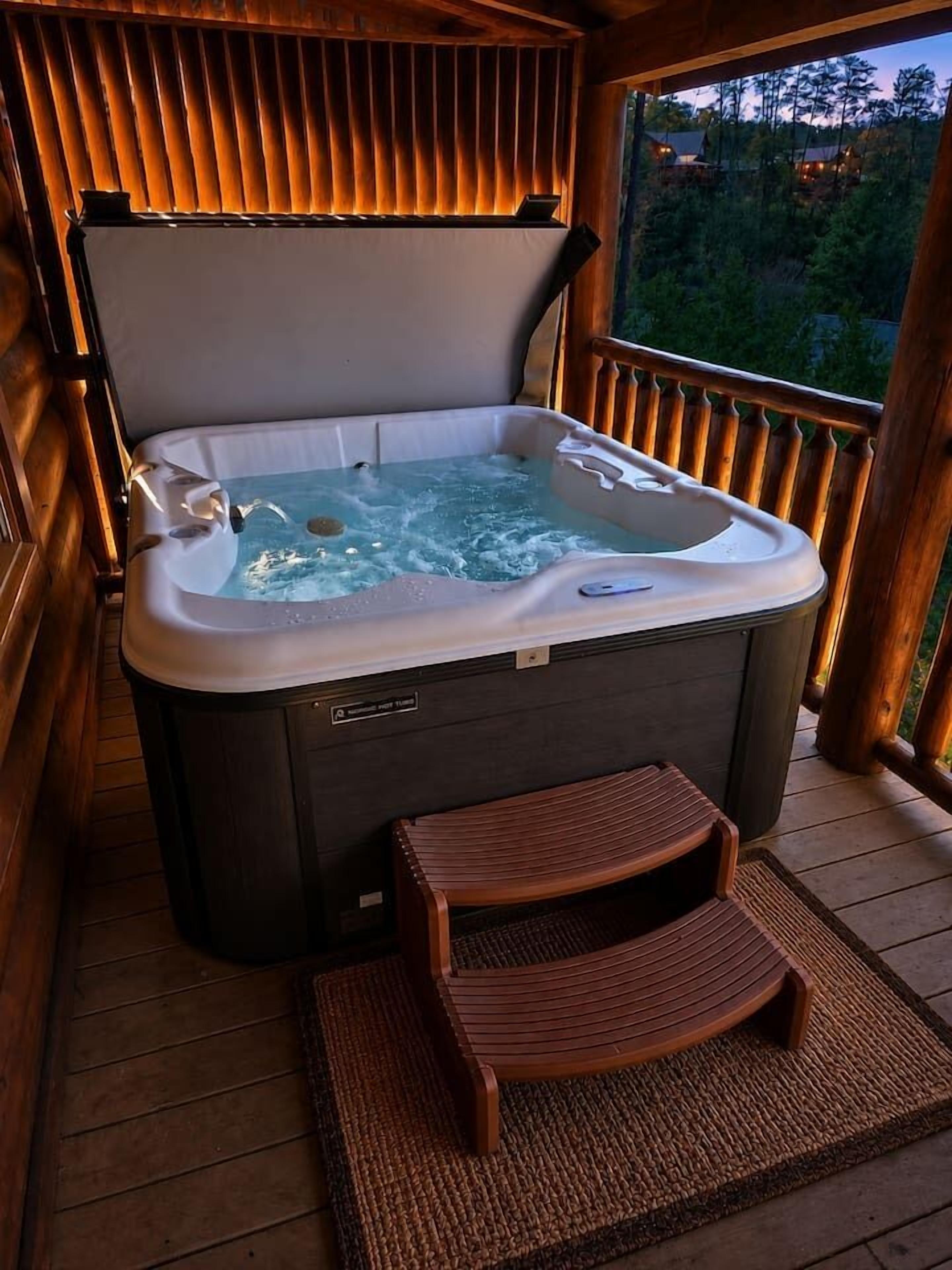 A hot tub on a wooden deck with a bench and a view of trees.