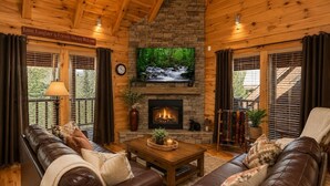 Ein gemütliches Wohnzimmer mit Kamin, Ledersofas, einem Couchtisch und einem über dem Kamin montierten Fernseher.