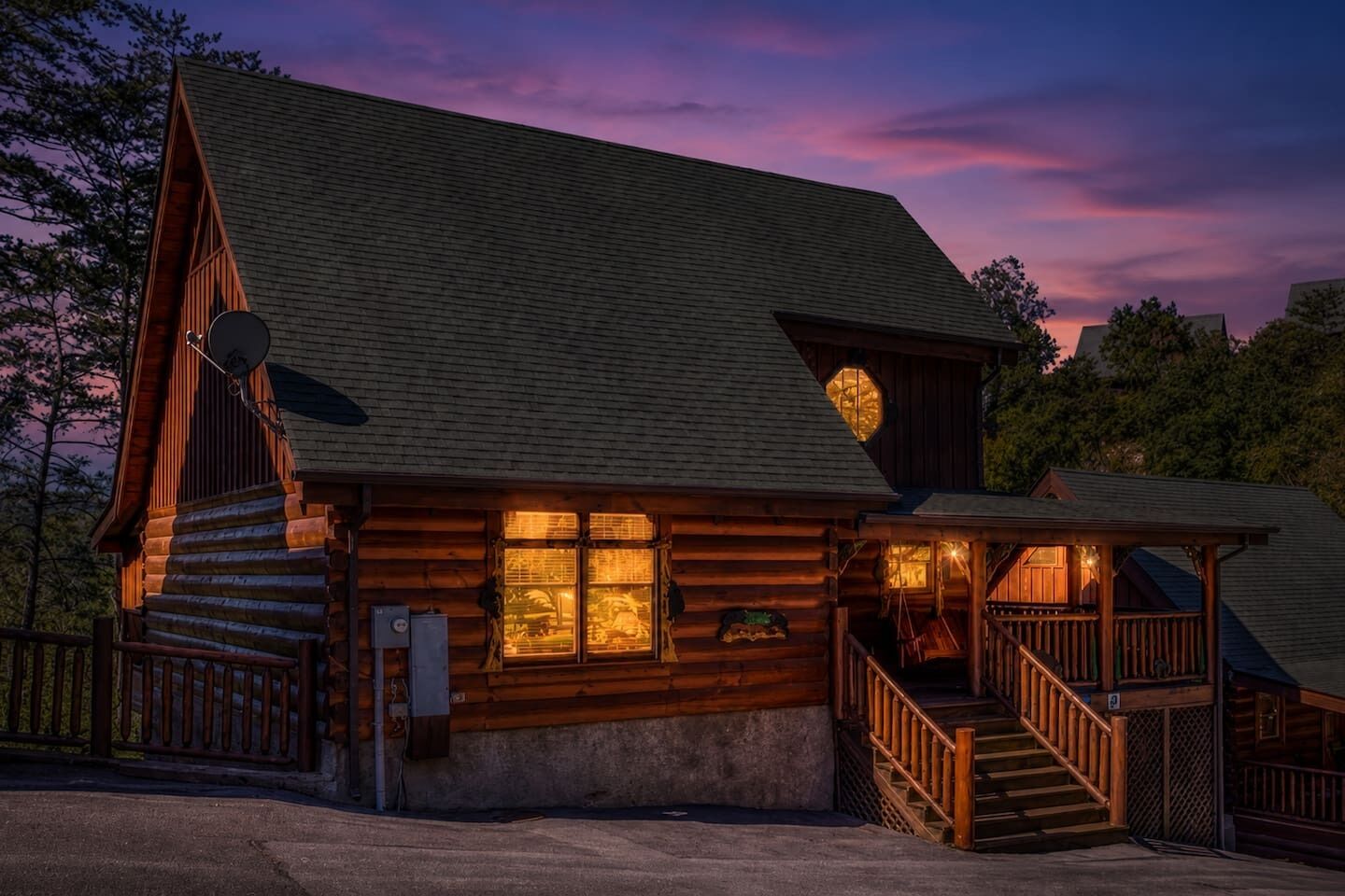 A log cabin with a porch, a satellite dish, and a staircase leading to the entrance.