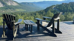Una terraza con sillas Adirondack que ofrece vistas a un paisaje montañoso.