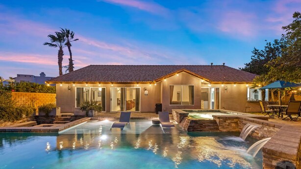 A house with a swimming pool, a waterfall feature, and outdoor seating. - Sandpiper by Nest Villas | 5BR Estate | Large Pool (Indio)