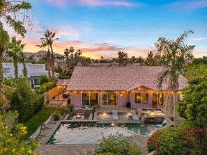 A house with a swimming pool, surrounded by greenery and palm trees. - Sandpiper by Nest Villas | 5BR Estate | Large Pool (Indio)