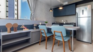 A modern kitchen with a built-in refrigerator, a dining table with chairs, and a window with curtains. - Rooftop#1101 - Luxury Apartment By Carpediem (Recife)