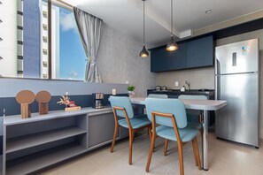 Eine moderne Küche mit Einbaukühlschrank, einem Esstisch mit Stühlen und einem fenster mit Vorhängen.