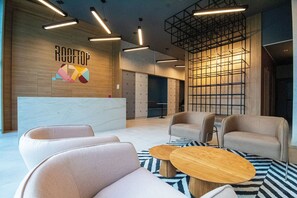 Eine moderne Lobby mit einer Rezeption, einer Sitzecke und Schließfächern.