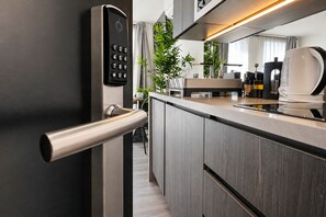 A modern kitchen with a built-in oven, a coffee machine, and a sleek door handle.