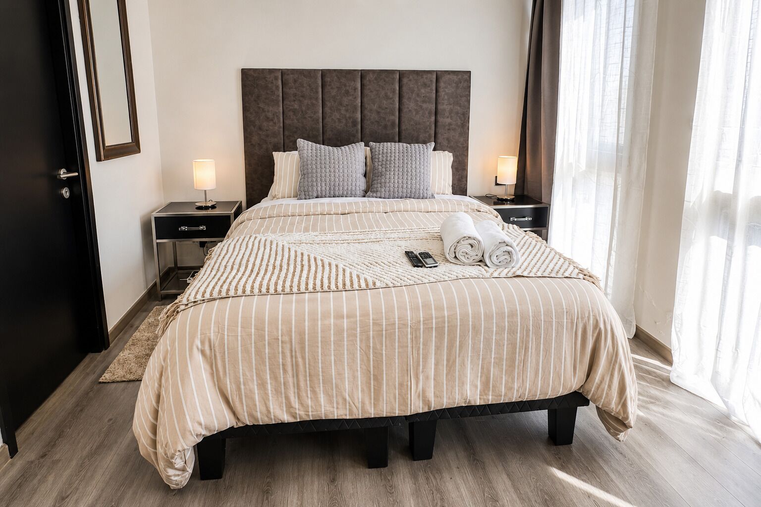 Habitación de hotel con una cama grande, dos mesitas de noche, una alfombra y una ventana con cortinas.