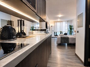 A modern kitchen with a built-in stove, a coffee maker, and a dining area with a table and chairs. - General Bulnes 259 (Santiago)