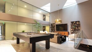 A modern interior with a pool table, a sofa, a TV, and a staircase. - General Bulnes 259 (Santiago)