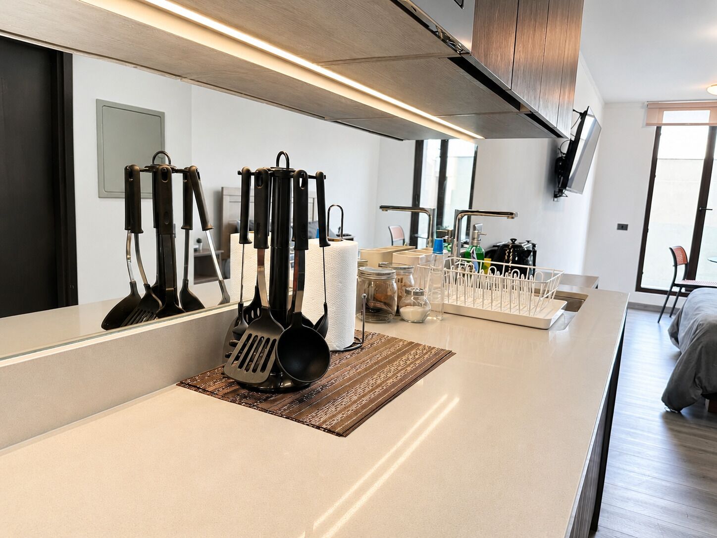 A modern kitchen with a central island, stainless steel appliances, and a large mirror.