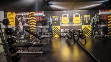 Un gimnasio con equipo de levantamiento de pesas, carteles motivacionales y un espejo grande.