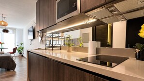 A modern kitchen with dark wood cabinets, a stainless steel range hood, and a built-in oven. - General Bulnes 259 (Santiago)