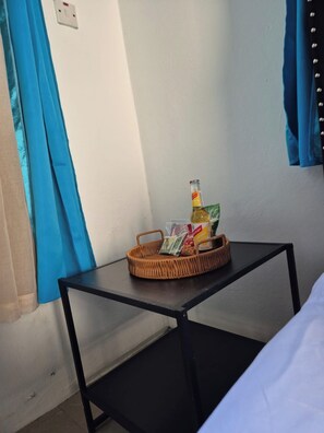 A room with a bed, a small table with a bottle and snacks, and blue curtains. - Burwood Breeze Retreat AC + WiFi + Hot water (Retreat Heights)