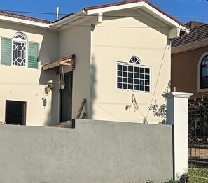 A residential building with a beige facade, a black door, a small window with a grid pattern, and a white window with a grid pattern. - Burwood Breeze Retreat AC + WiFi + Hot water (Retreat Heights)