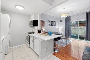 A modern kitchen with white cabinets, a built-in microwave, and a gas stove. - Walk to Piedmont Park | Free Parking | City Views (Atlanta)
