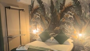 A hotel room with a bed, a wall-mounted air conditioner, and a tropical-themed mural. - Pisacane Family Sea (Naples)