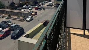 A balcony with a view of a parking lot and buildings. - Pisacane Family Sea (Naples)