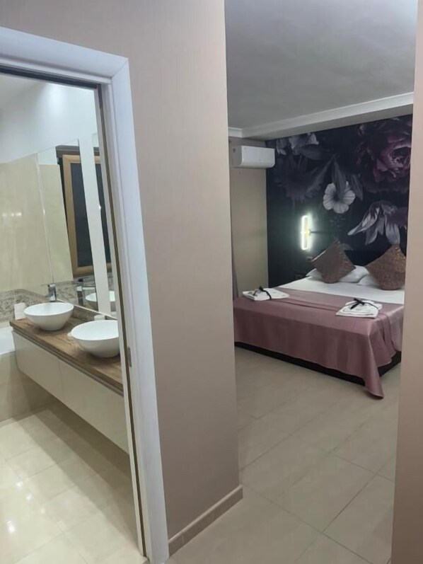 A bathroom with a large mirror, two sinks, and a bathtub.