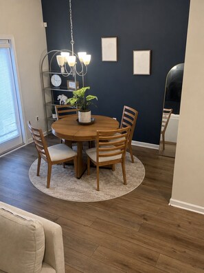 A dining area with a round wooden table, four chairs, a chandelier, and a potted plant. - Pleasant 3-bedroom townhome in Southwest Atlanta (Atlanta)