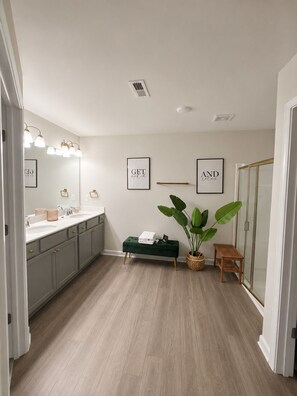 A bathroom with a double vanity, a green bench, a potted plant, and two framed motivational quotes on the wall. - Pleasant 3-bedroom townhome in Southwest Atlanta (Atlanta)